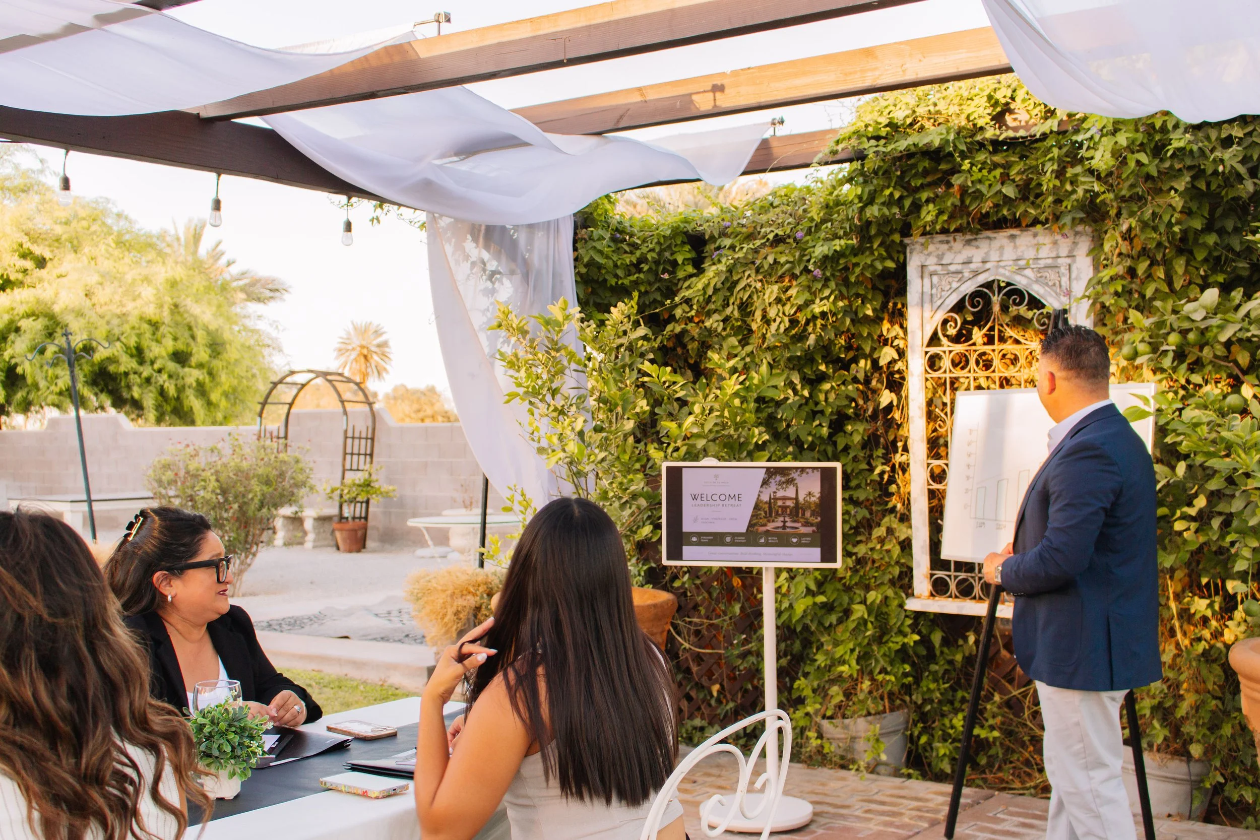 Business presentation held outdoors beneath Villa de la Meza's pergola event space.