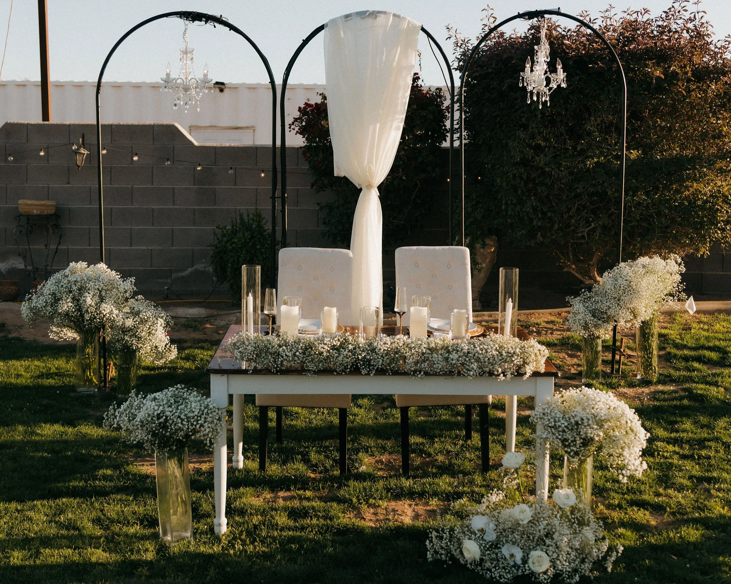 Chandelier ceremony arches prepared for an outdoor celebration.