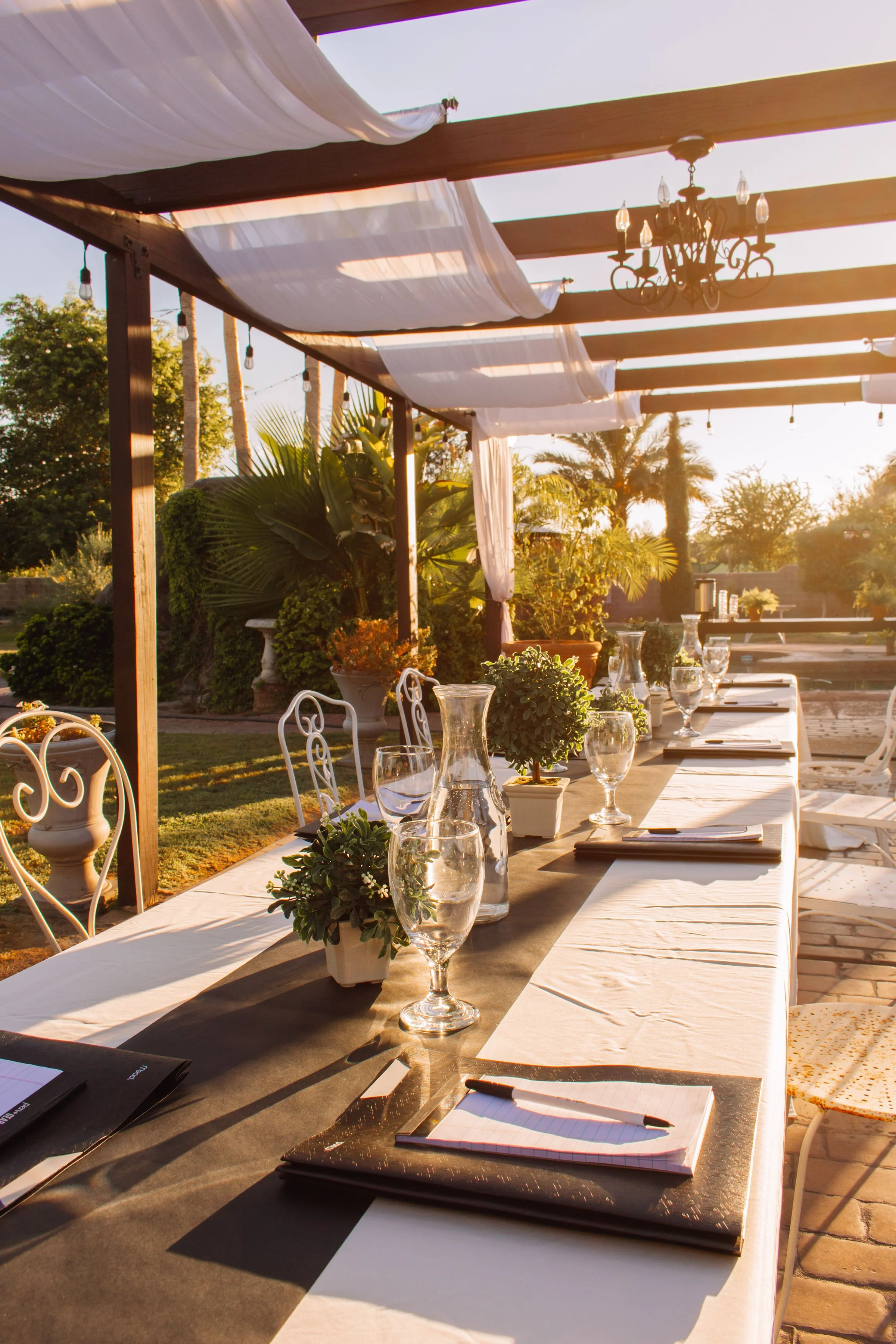 Elegant outdoor conference table setup beneath pergolas at Villa de la Meza corporate event venue.