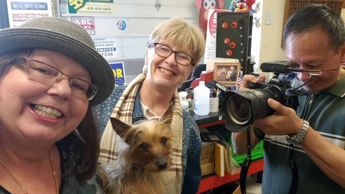 Kathi Santora (c) on assignment for Harford Magazine and the feature story Loosening their collars: Schools and businesses that have pets who “work” in the office . (L) Paula Cassagrande, owner of Big House Signs in Havre de Grace (with Shorty) and Ken Lam, Baltimore Sun photographer.