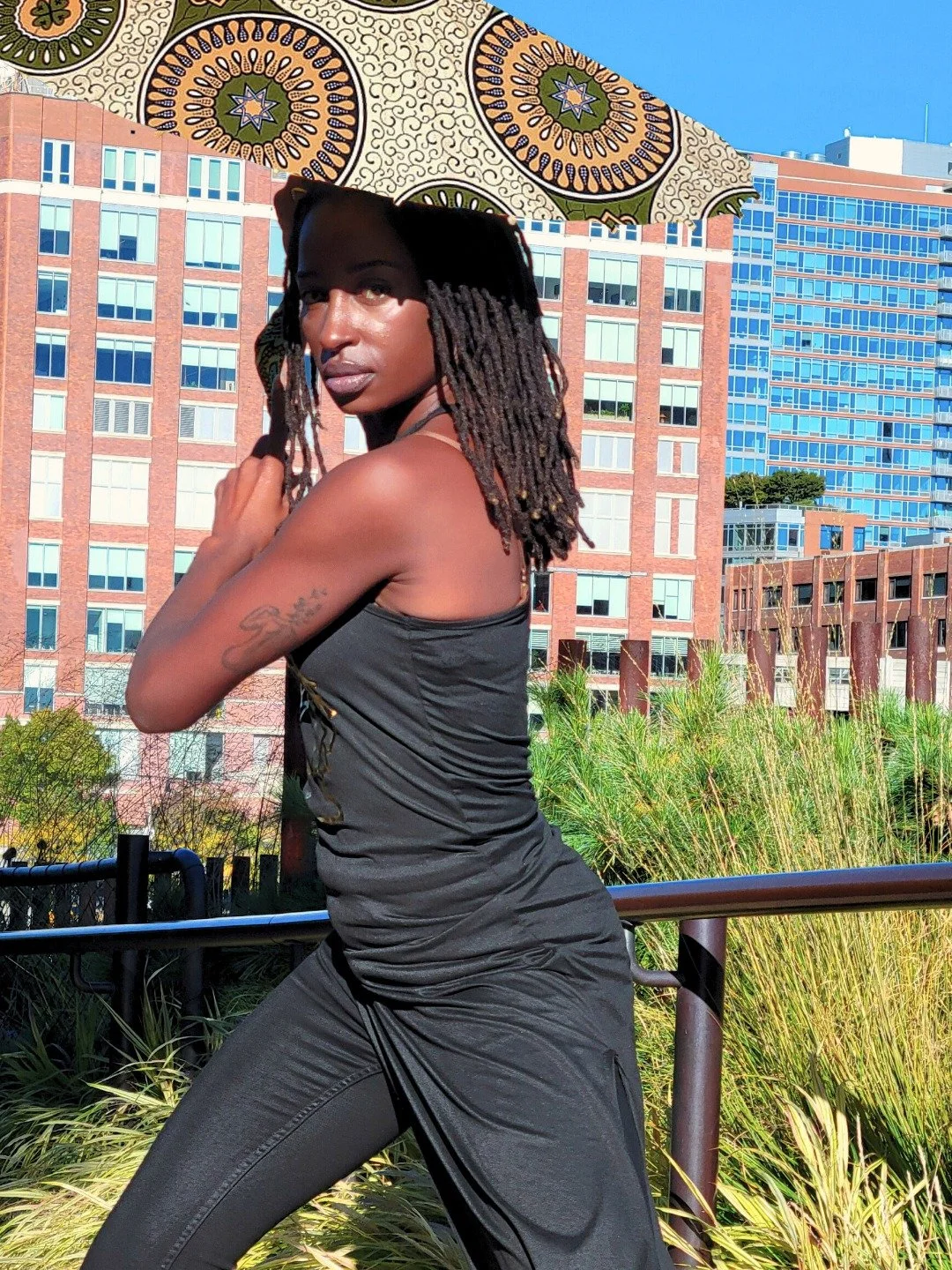 She moves with the measured calm of roots and sunlight, each shift of weight mirrored in the gentle sweep of green, and terracotta above her. Balance is not stillness, but a living rhythm, and the parasol follows her, a quiet companion reflecting the