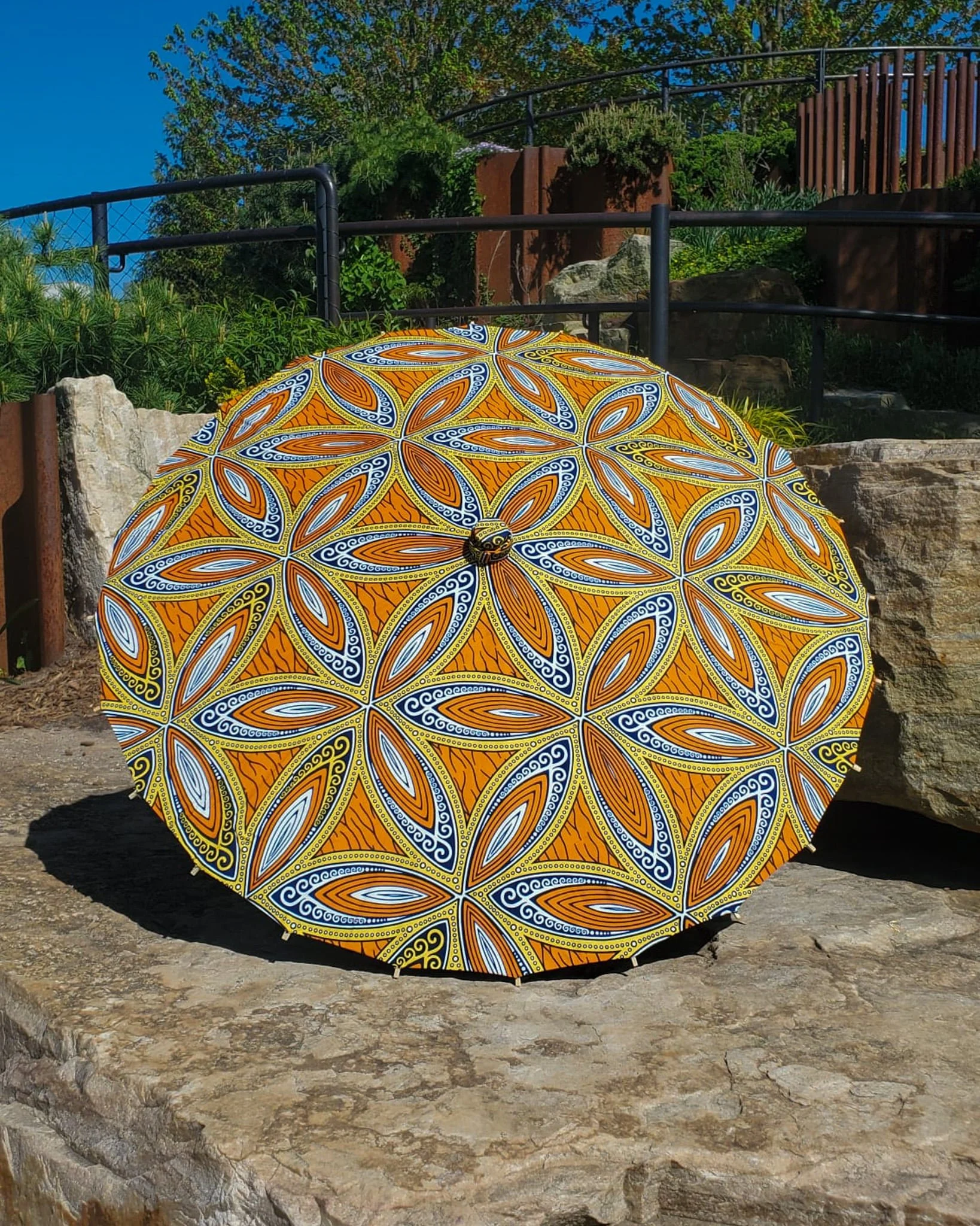 nellite handmade parasol exterior, medium size, with afro-inspired design on a stone slab