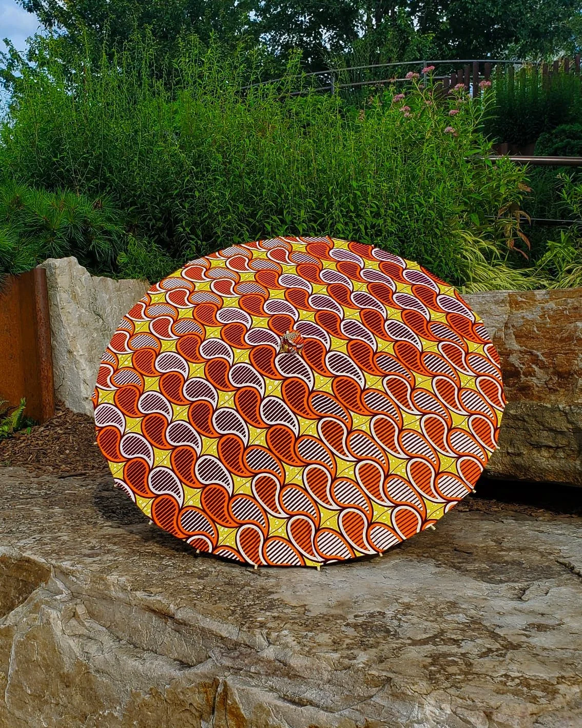 amber handmade parasol exterior, medium sized, with afro-inspired design on a stone slab