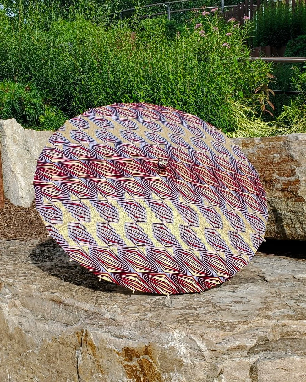 strawberry quartz handmade parasol exterior, medium size, with afro-inspired design on a stone slab