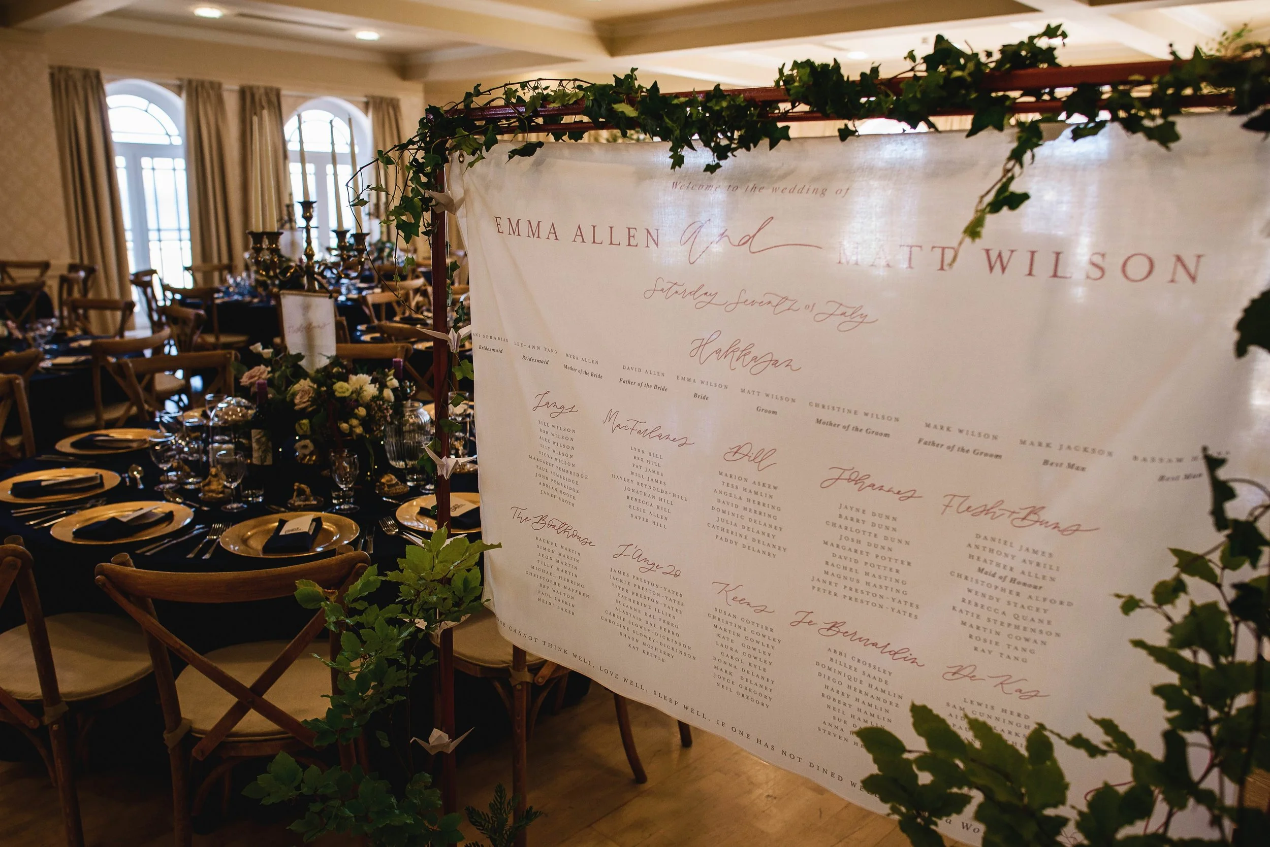 Fabric printed table plan surrounded with ivy and hung from a custom built metal frame