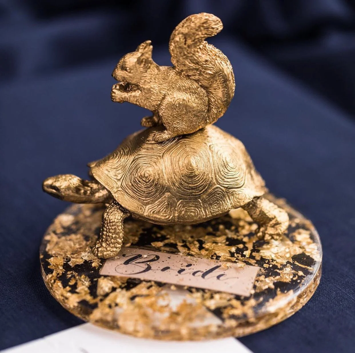 Name places as mini works of art. Calligraphy names laminated and sunk in the resin along with gold leaf. Cured in the sun and schleich animals spray painted gold and attached to give some whimsy to the table. 