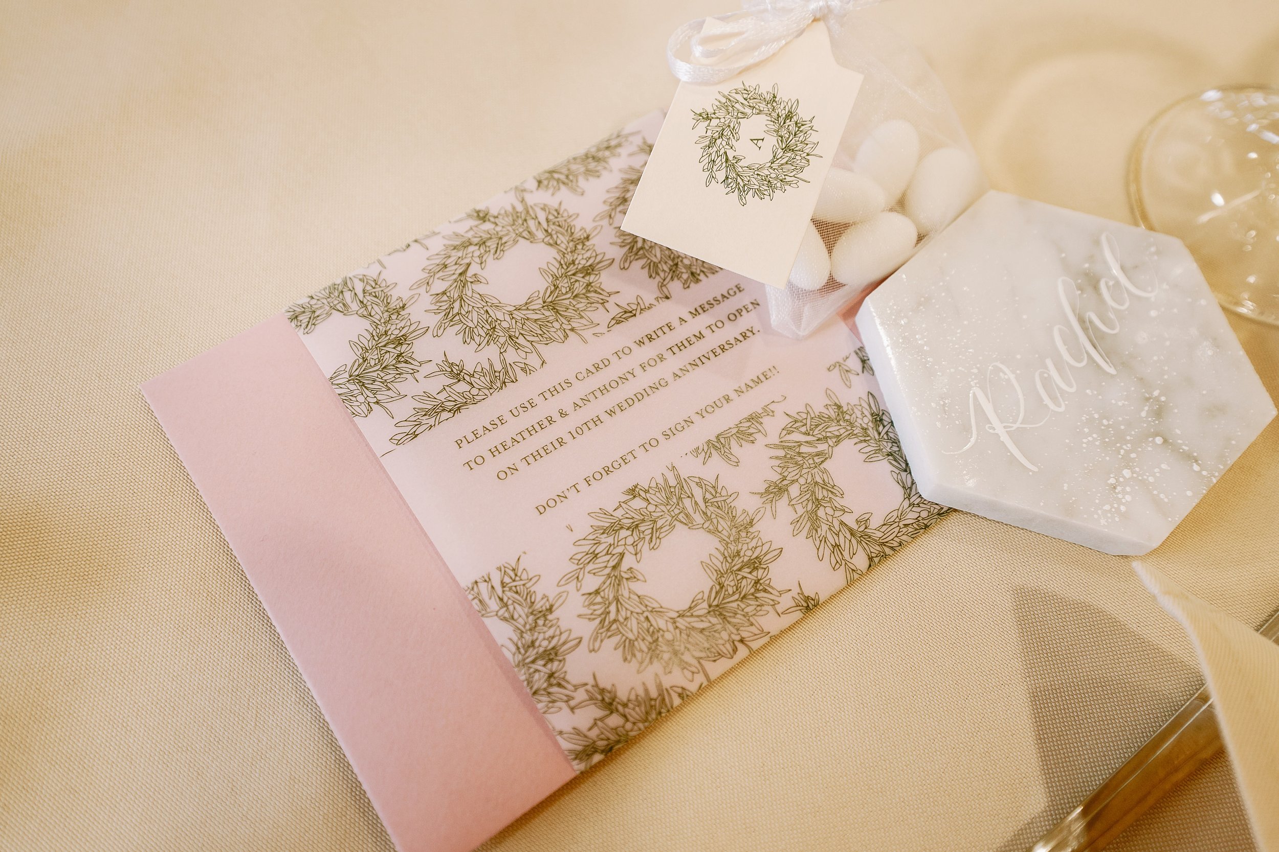 Envelopes with 10 year anniversary wishes, tags for almonds with the wedding logo and calligraphy marble tiles