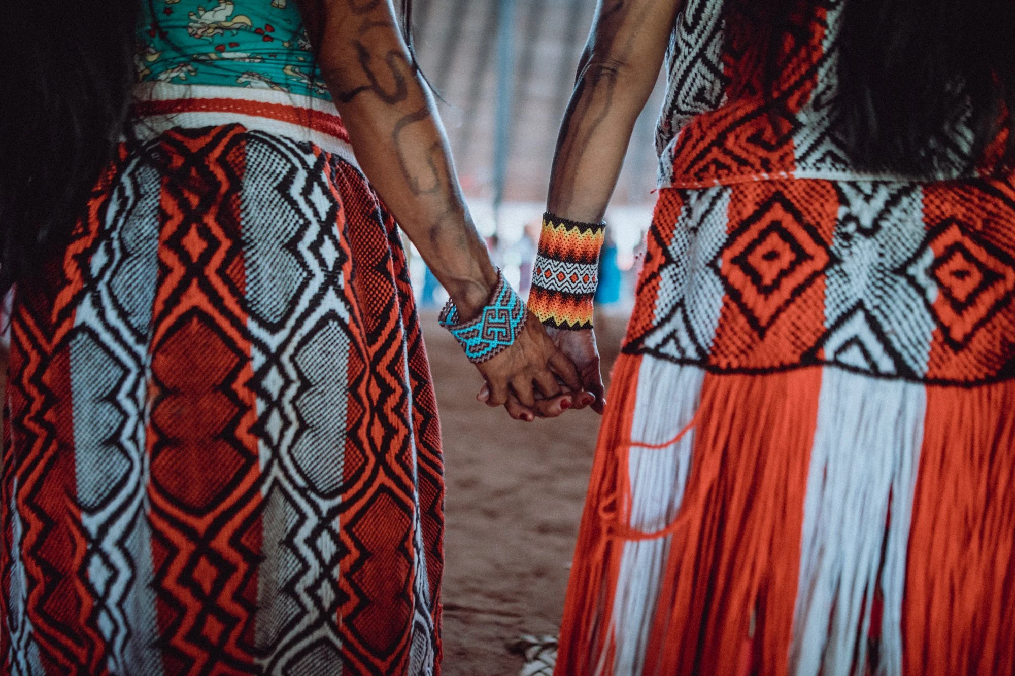 Two Indigenous Huni Kuin women holding hands in solidarity
