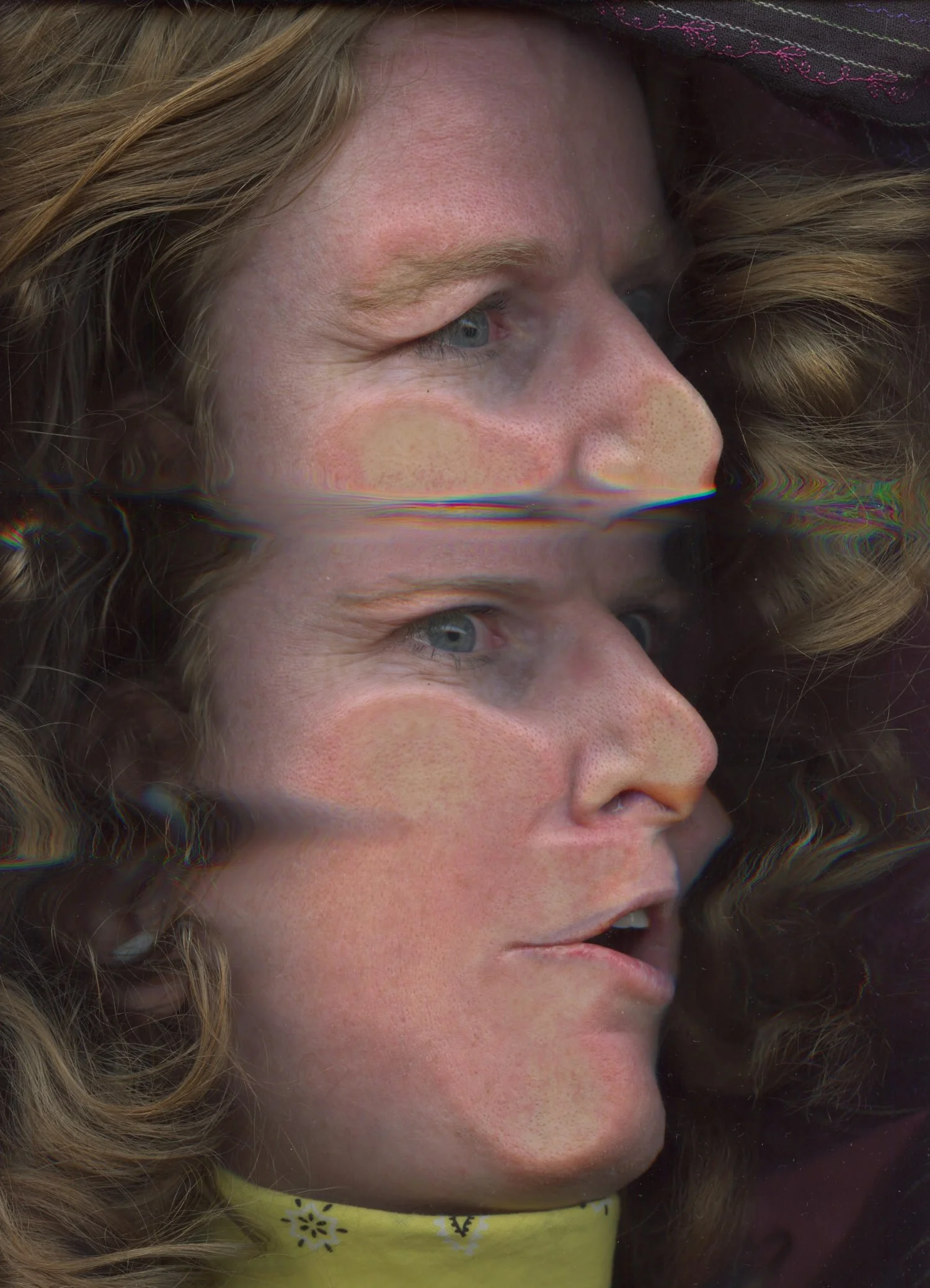 Portrait of a blonde woman: face smooshed sideways against the glass of a scanner, gaze unfixed, mouth parted. Repositioned mid-scan, the top half of her face repeats in fresh distortion, a slight glitch at the seam. Her hard blue eyes look away.