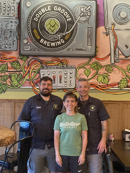 Double Groove Brewing team in front of decorated wall.