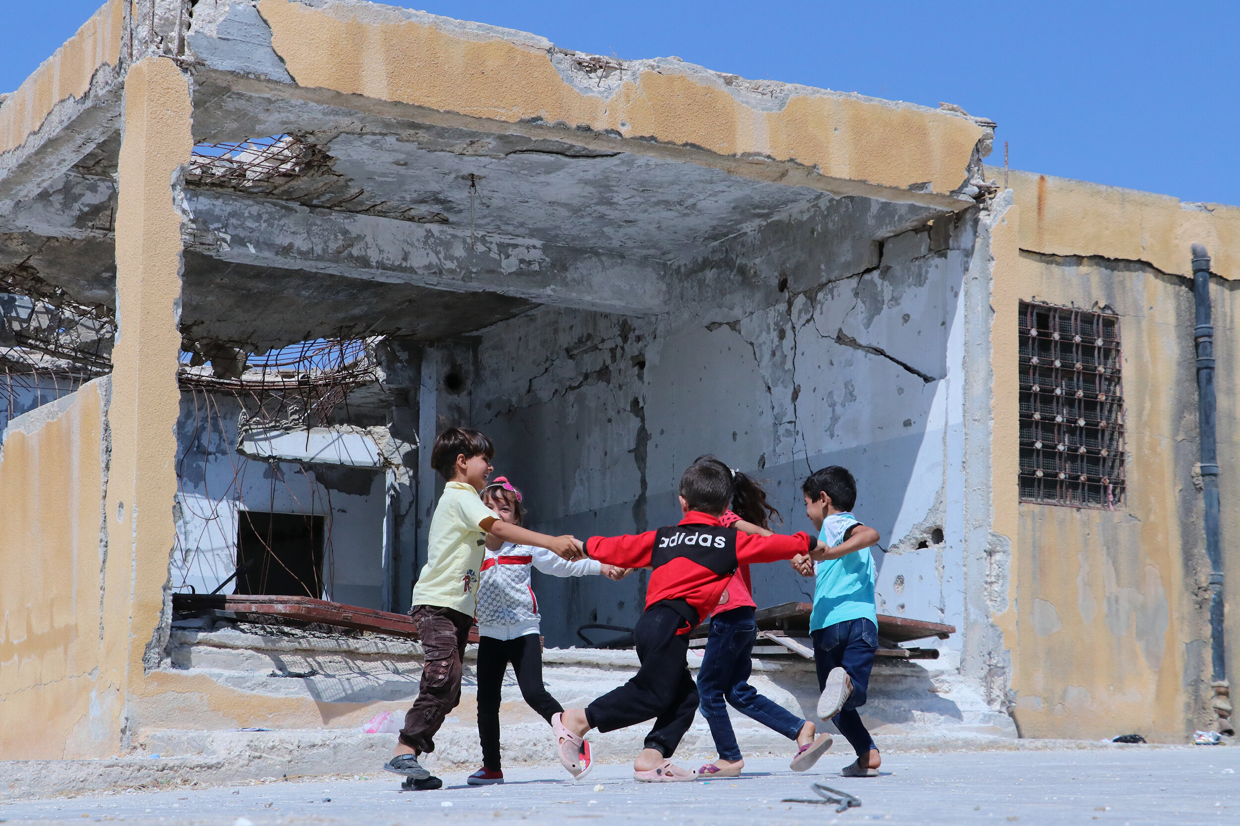 Children play outside their war-damaged school near Idlib, Syria. © 2019 Save the Children 