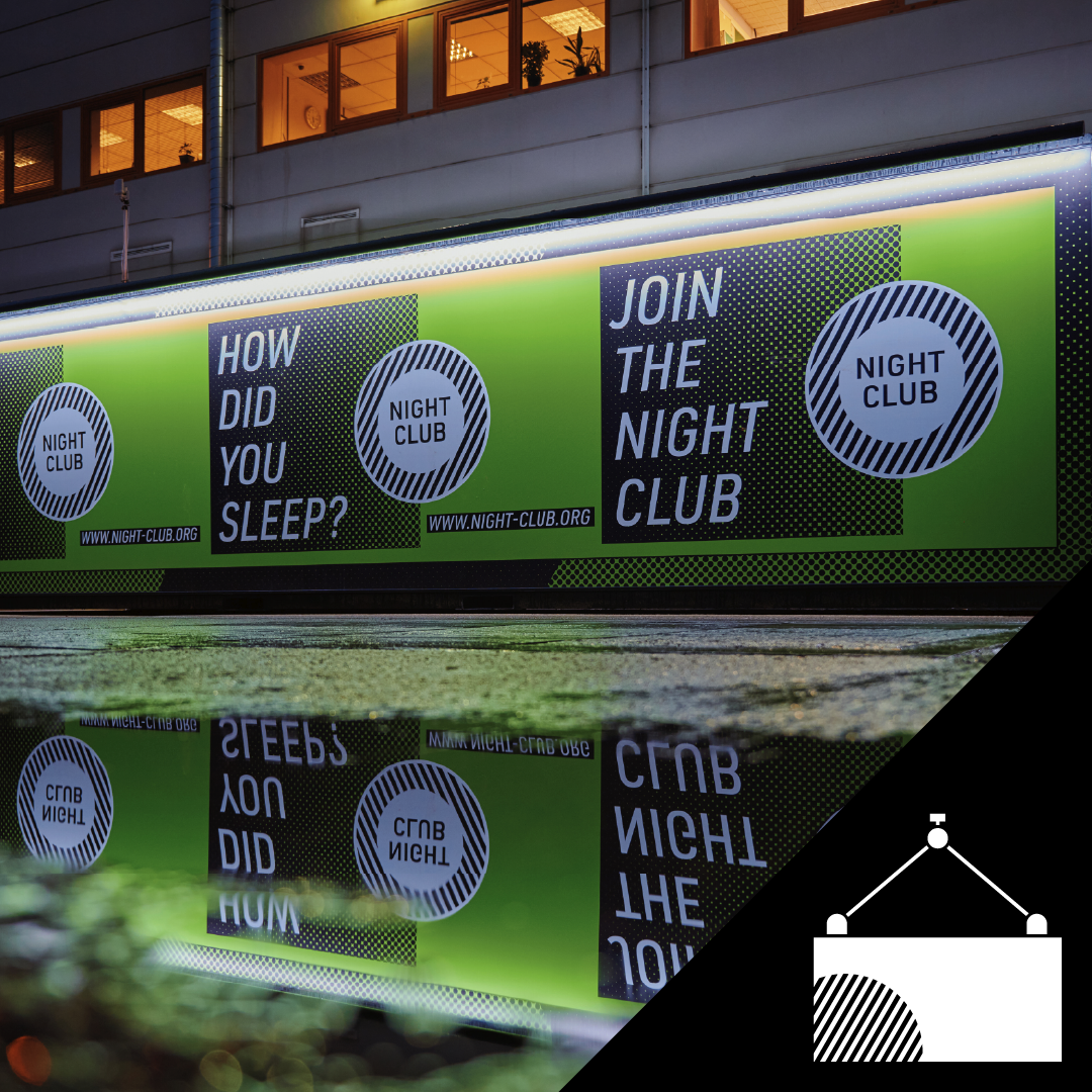 Backlit advertisement board outside a building promoting a night club, with green, black, and white graphics and text reading "Join the Night Club" and "How did you sleep?"