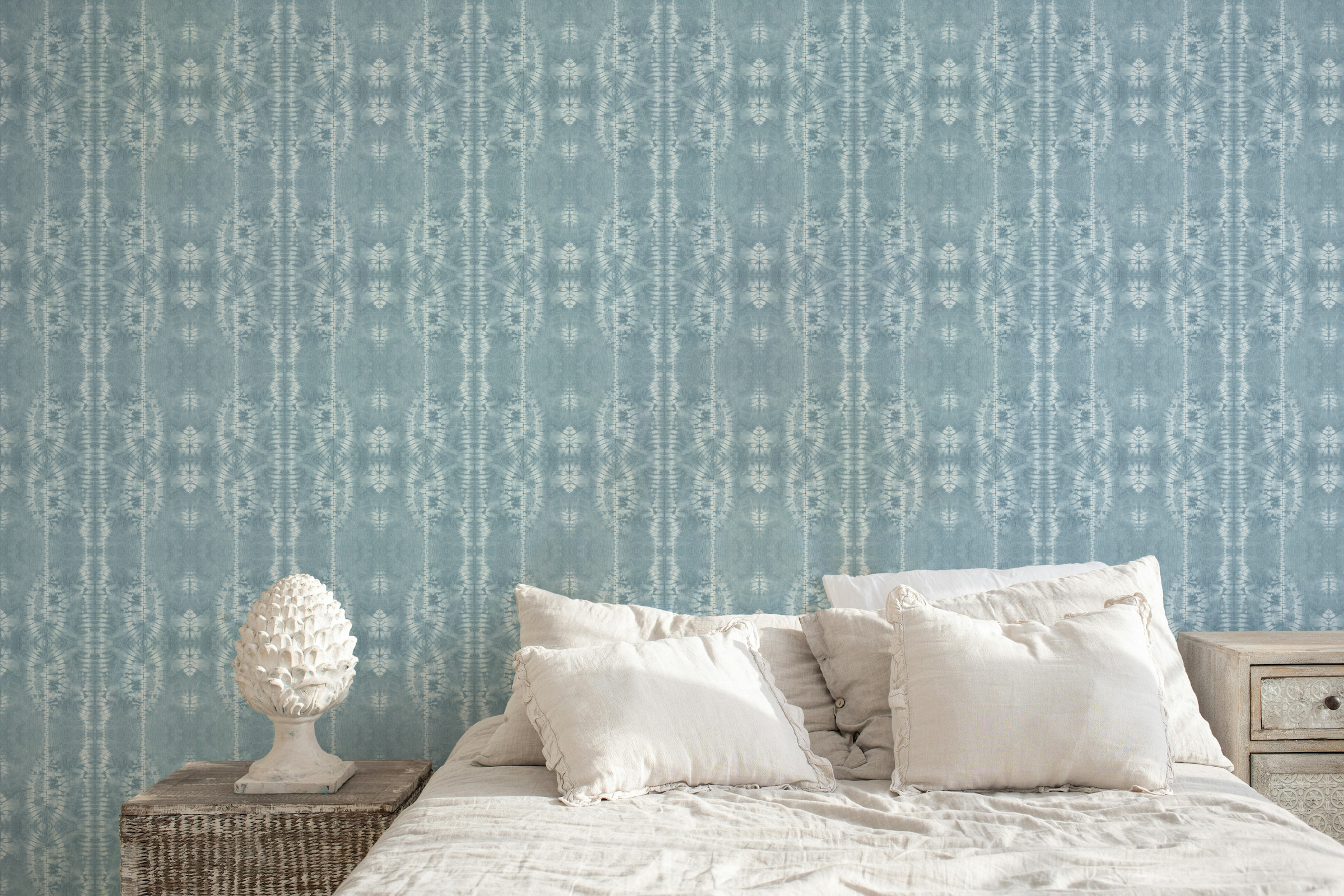 Original hand dyed blue shibori wallpaper featuring traditional Japanese resist dyed patterns displayed in a light, coastal inspired bedroom.
