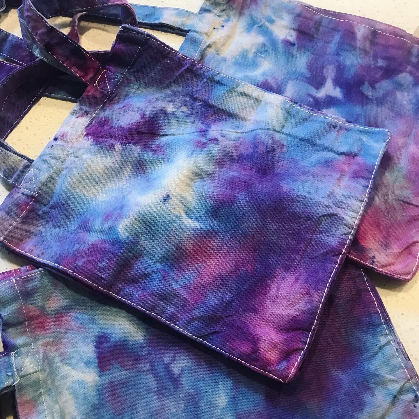 Ice dyeing with these baby bags as a test run. I've got 3 designs that will each have their own colorway. Ice dyeing is hella fun if you've never done it. This is just one dye color powder that gets all these neat color splits 💙💜💖

Bags will debut