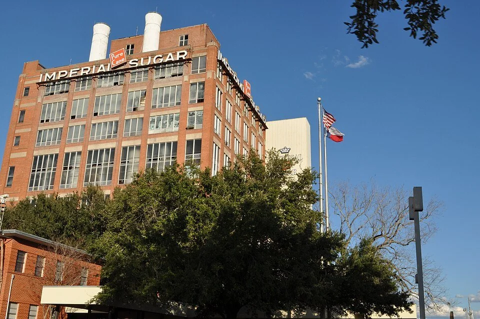 Imperial Sugar building in Sugar Land Texas with American and Texas flags and historic brick industrial architecture.