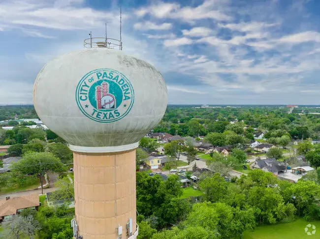 Pasadena Texas water tower with city seal, aerial view over residential neighborhood and trees under cloudy sky.