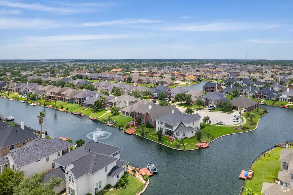 Aerial view of Houston suburban neighborhood with lakefront homes, backyards, docks, and curved residential streets.