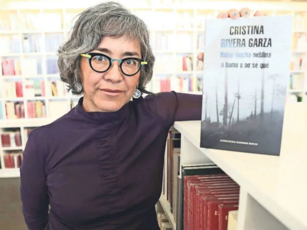 Cristina Rivera Garza aguantando un libro que no es el que estaba leyendo hoy pero que es igual de bueno.
