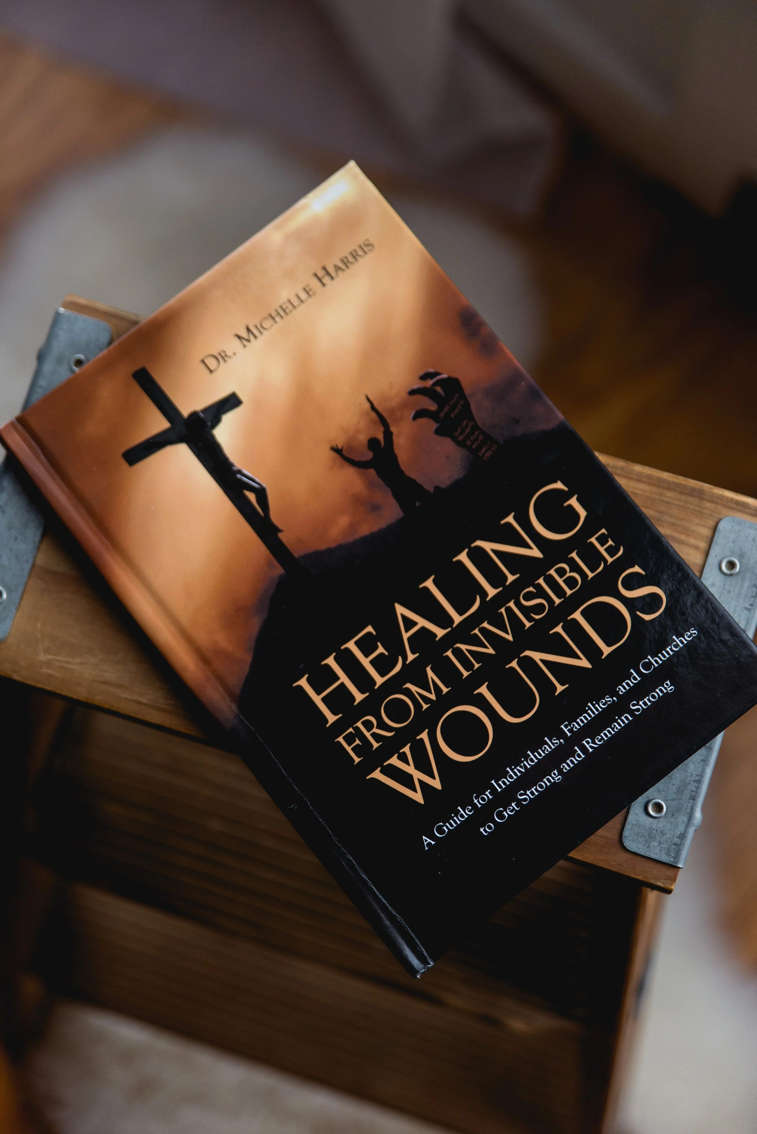 Book titled 'Healing from Invisible Wounds' by Dr. Michelle Harris resting on a wooden chair.