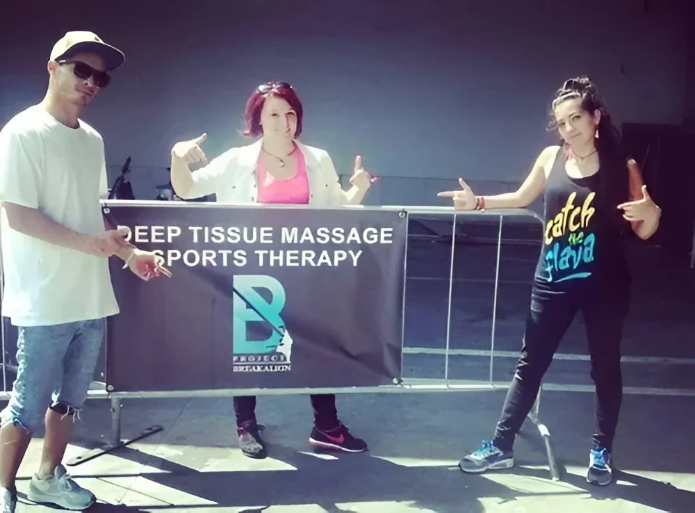 Three people standing behind a BSTT banner for deep tissue massage and sports therapy, outdoors, promoting rehabilitation and sports wellness services in Bristol
