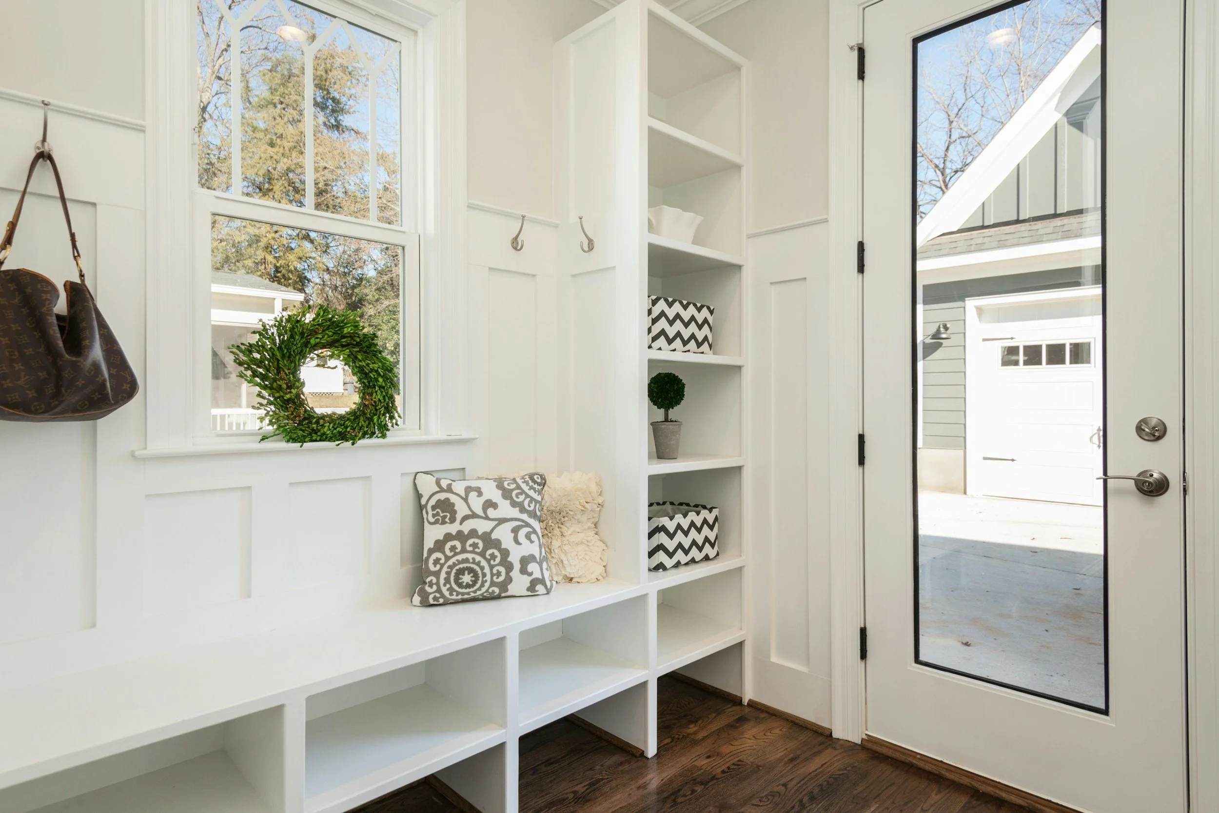 Mudroom with white shelving and chrome hooks to hold purses and coats