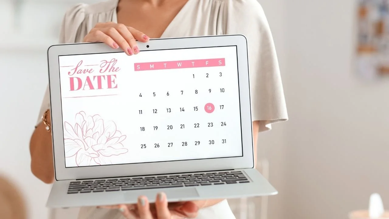 Woman holding a laptop facing out at the camera. The laptop has a Save the Date title and a calendar visible.