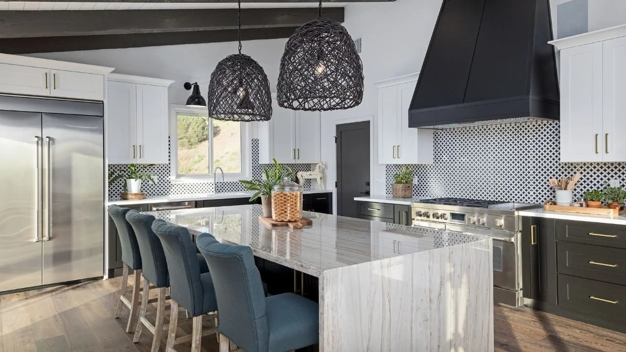 Image of a beautiful kitchen in Lake Forest that has a large double wide refridgerator, blue island chairs, and black accents on the ceiling, lighting, and stove hood.