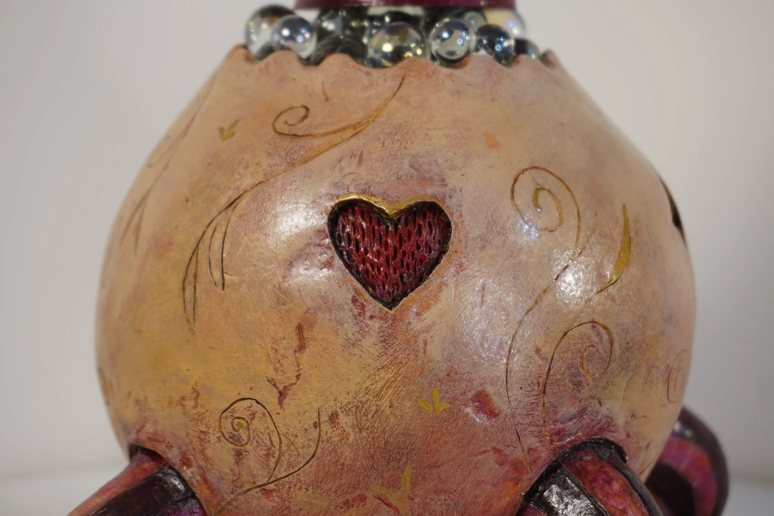Close-up of a creature with heart-shaped opening, curly lines, and beads on top of its head.