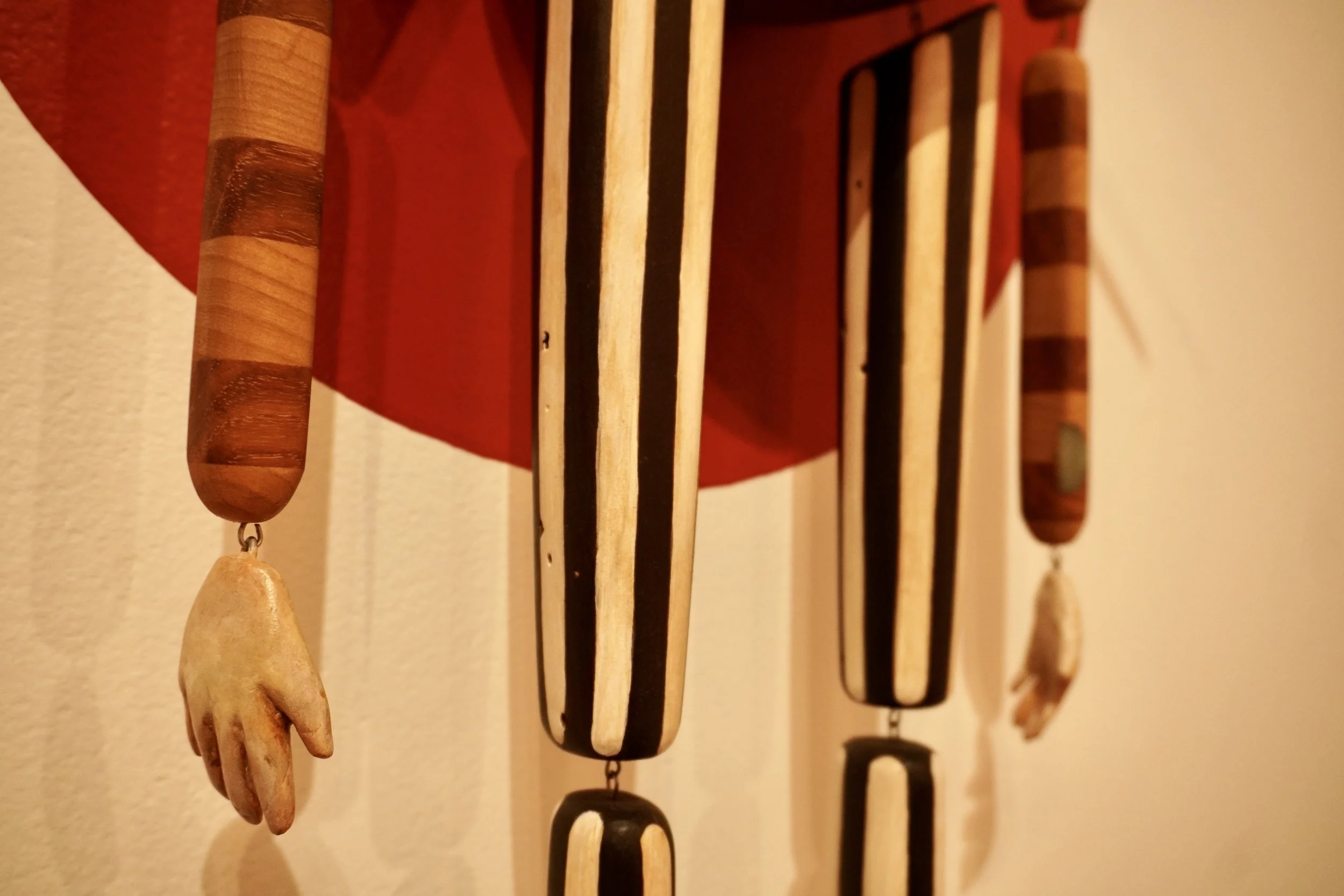 Close-up of wooden wind chimes hanging against a light-colored wall.