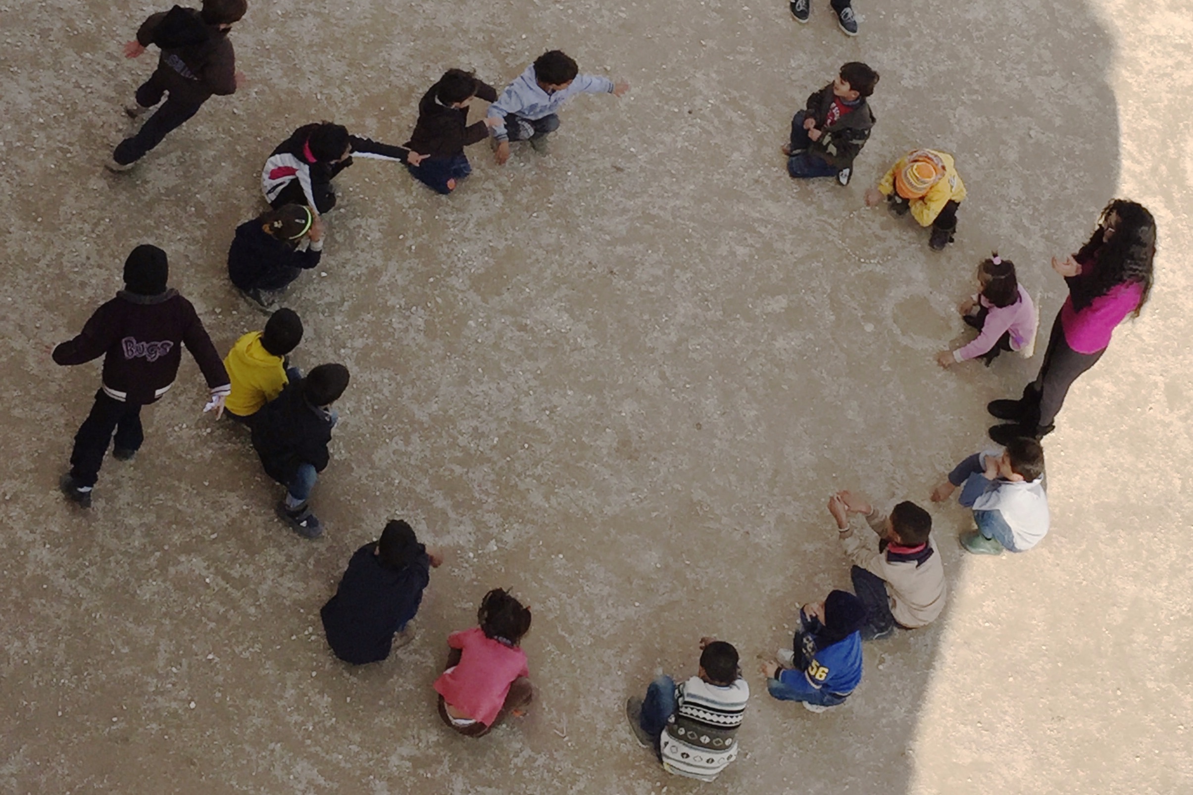Young Syrian children in Lebanon sitting outside in a circle. Photo: Elizabeth Adelman