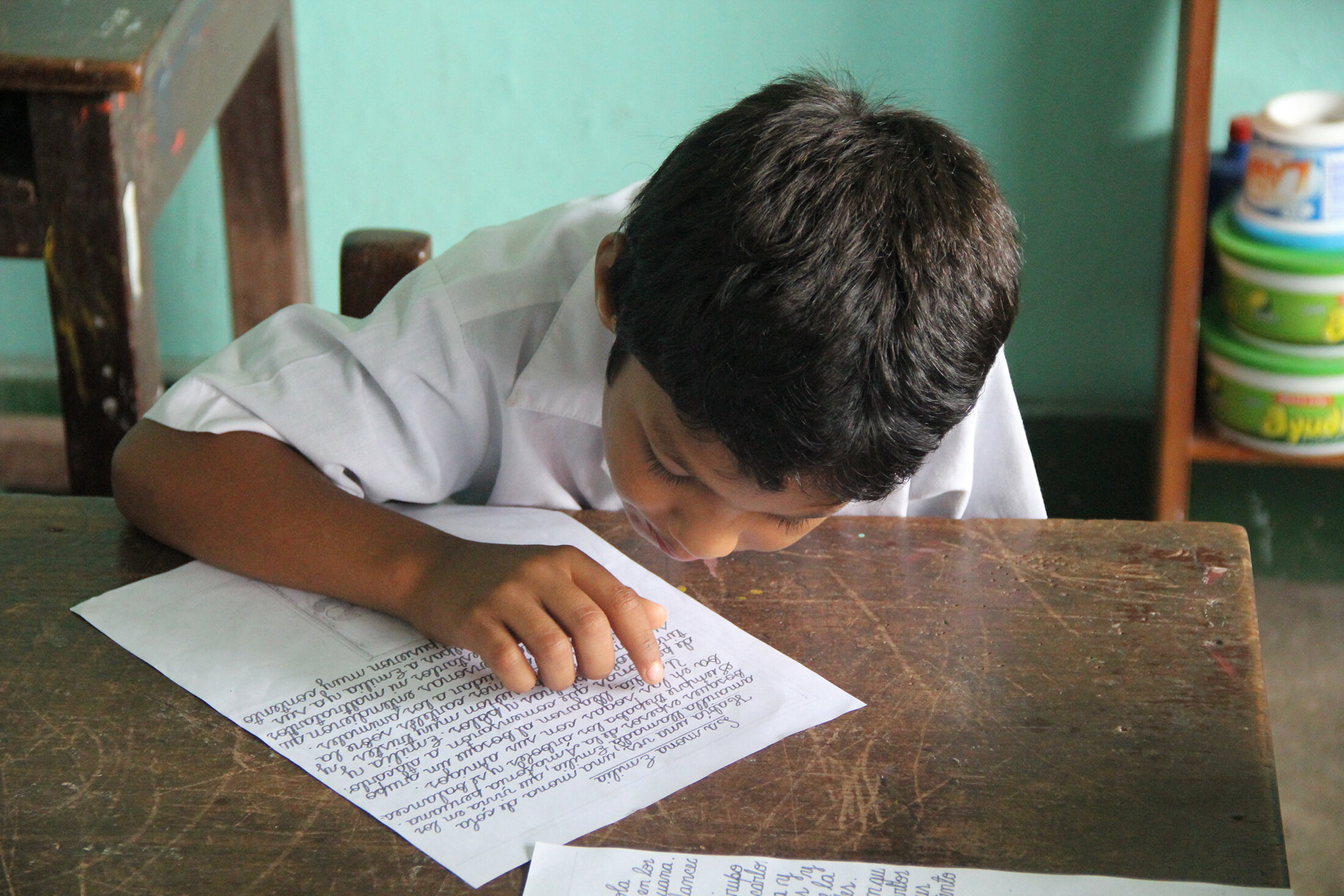 Young Peruvian boy practices reading while sitting at a desk. Photo: Elizabeth Adelman