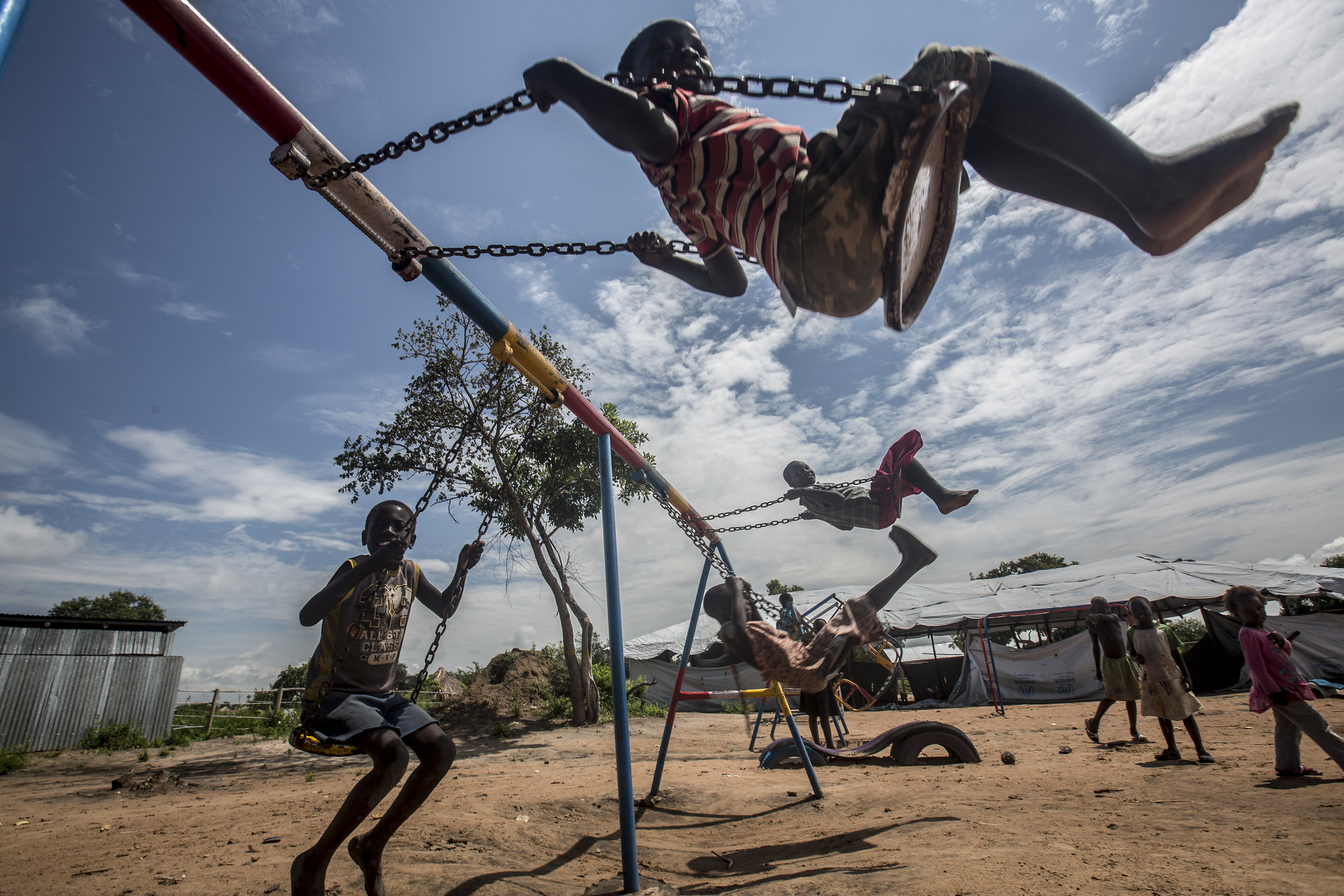 Children play on a swing at Rhino refugee settlement in Uganda. Photo: EU/ECHO/Edward Echwalu