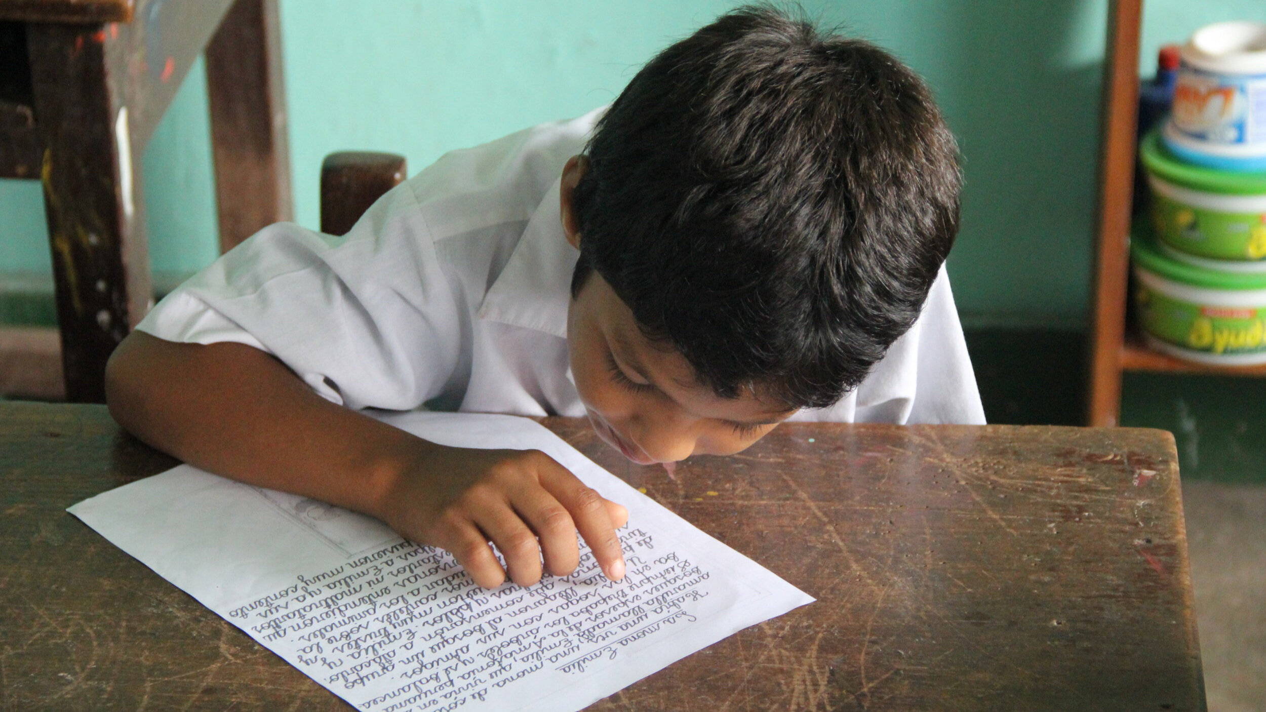 Young Peruvian boy practices reading while sitting at a desk. Photo: Elizabeth Adelman