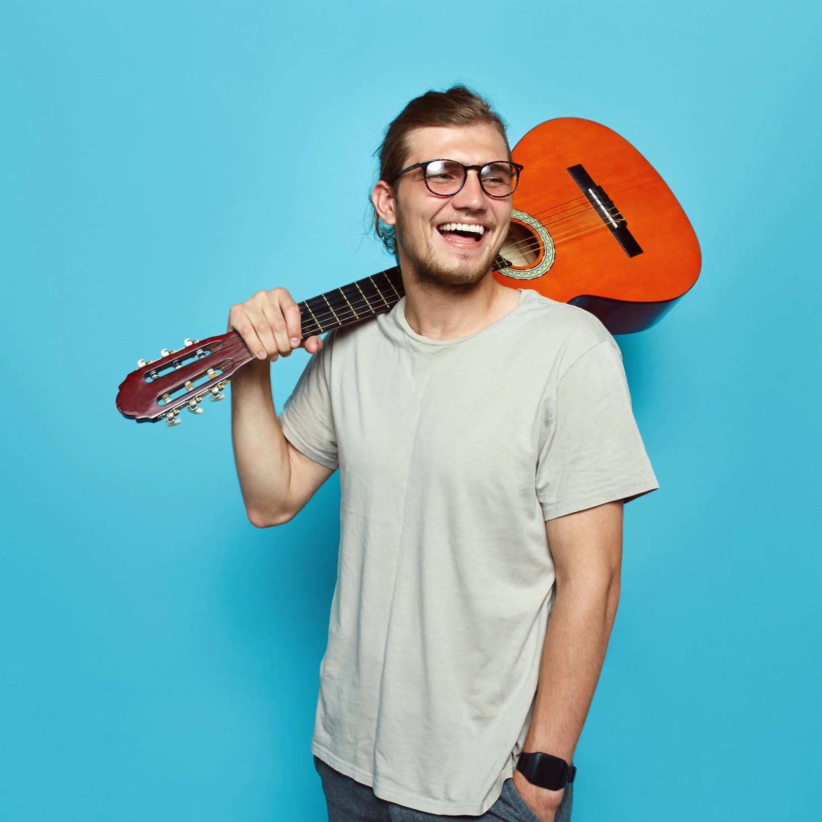 Professional singer-songwriter smiling holding a guitar over his shoulder..