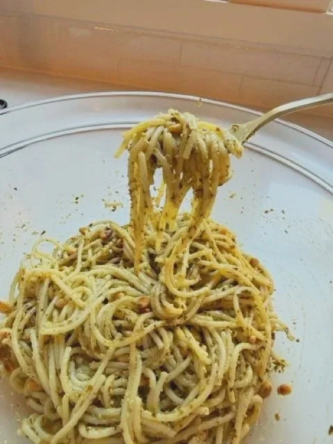 Easy weeknight pesto pasta with toasted pine nuts in a glass bowl