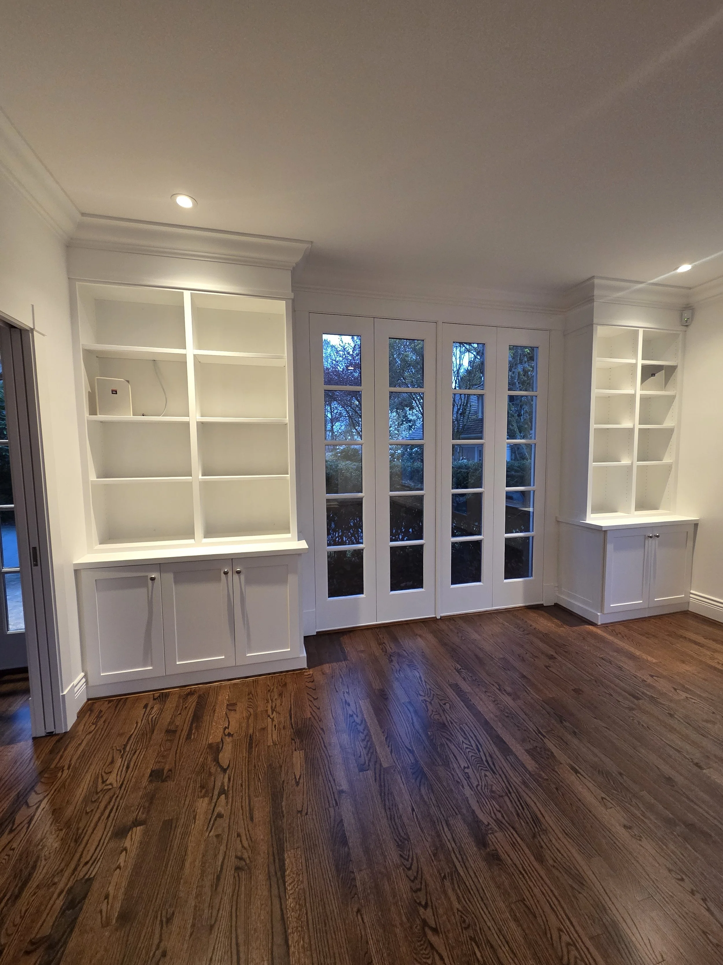 Custom white shelving and base cabinets framing the glass doors.