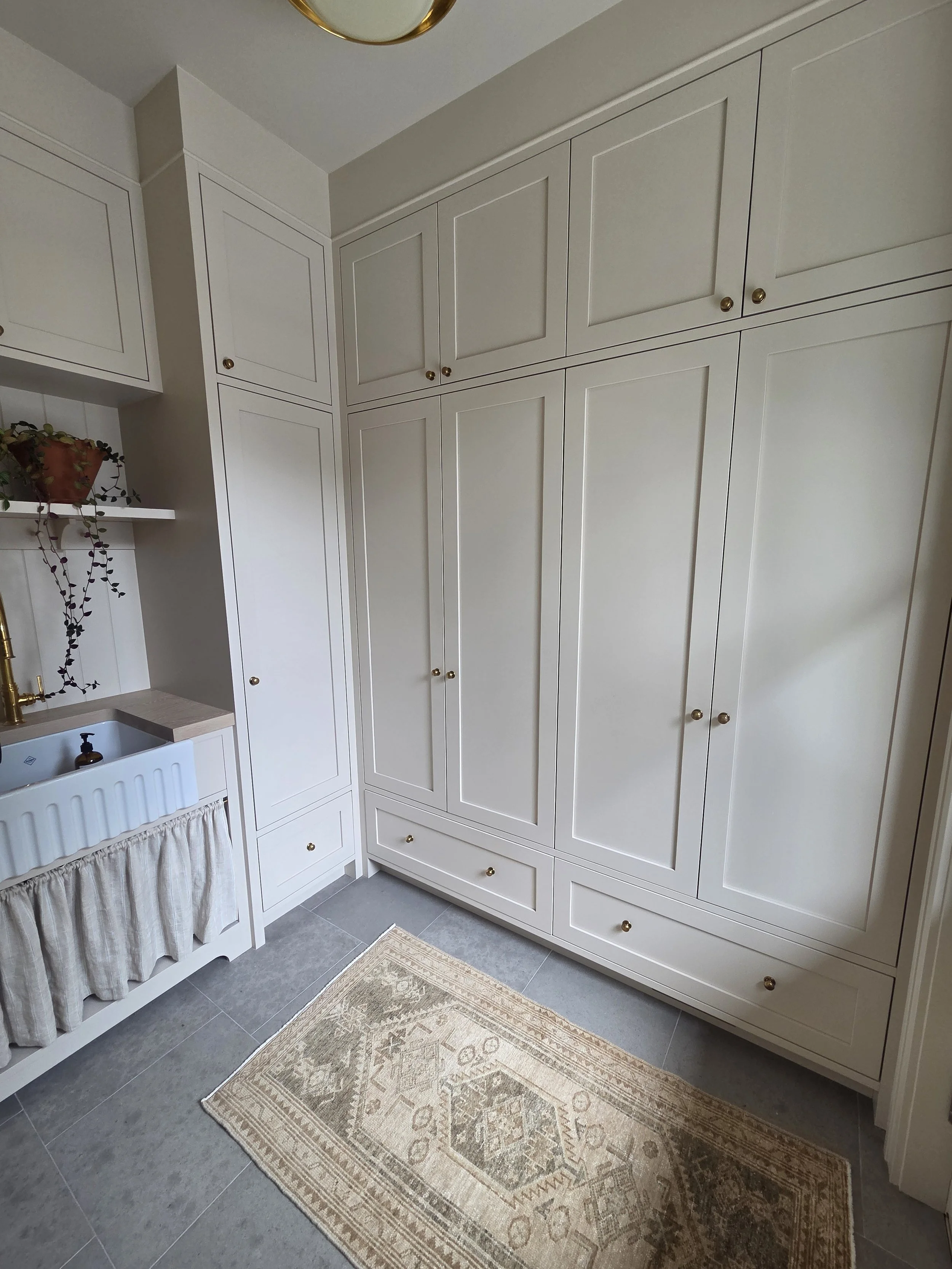 Tall white pantry cabinetry with brass hardware and lower drawers.