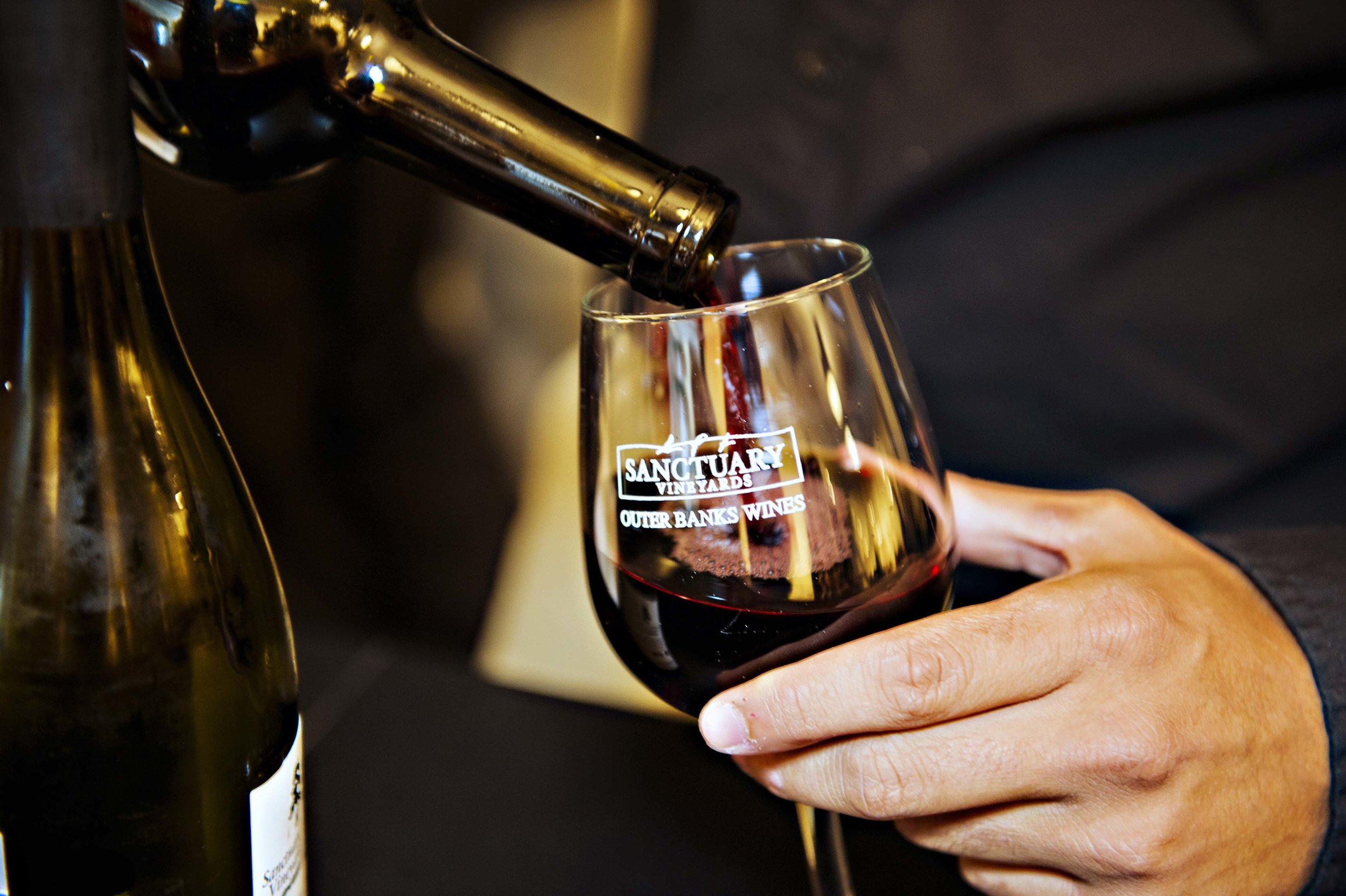 Outer Banks wine maker pours red wine into a Sanctuary Vineyards glass in Outer Banks Wine Country. 