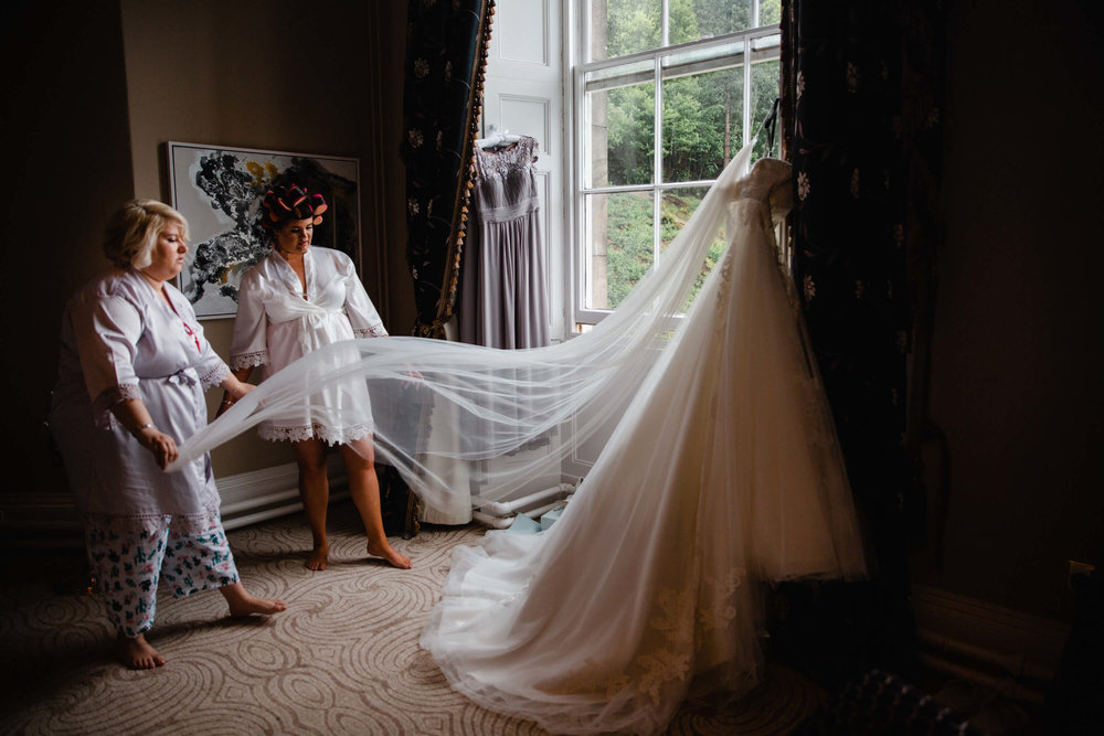 bridesmaid holding wedding dress veil in bridal suite at haigh hall