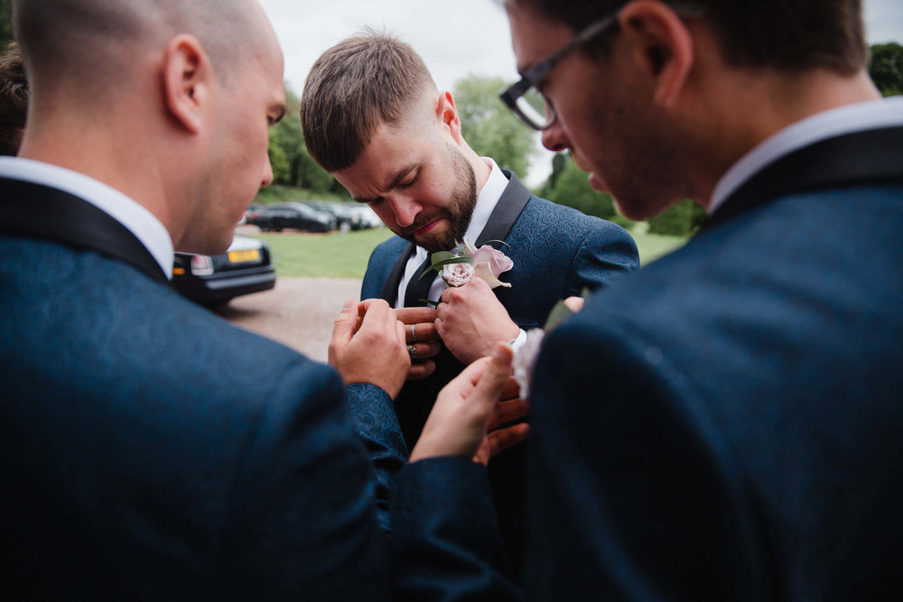 usher fixing button hole flower to jacket lapel