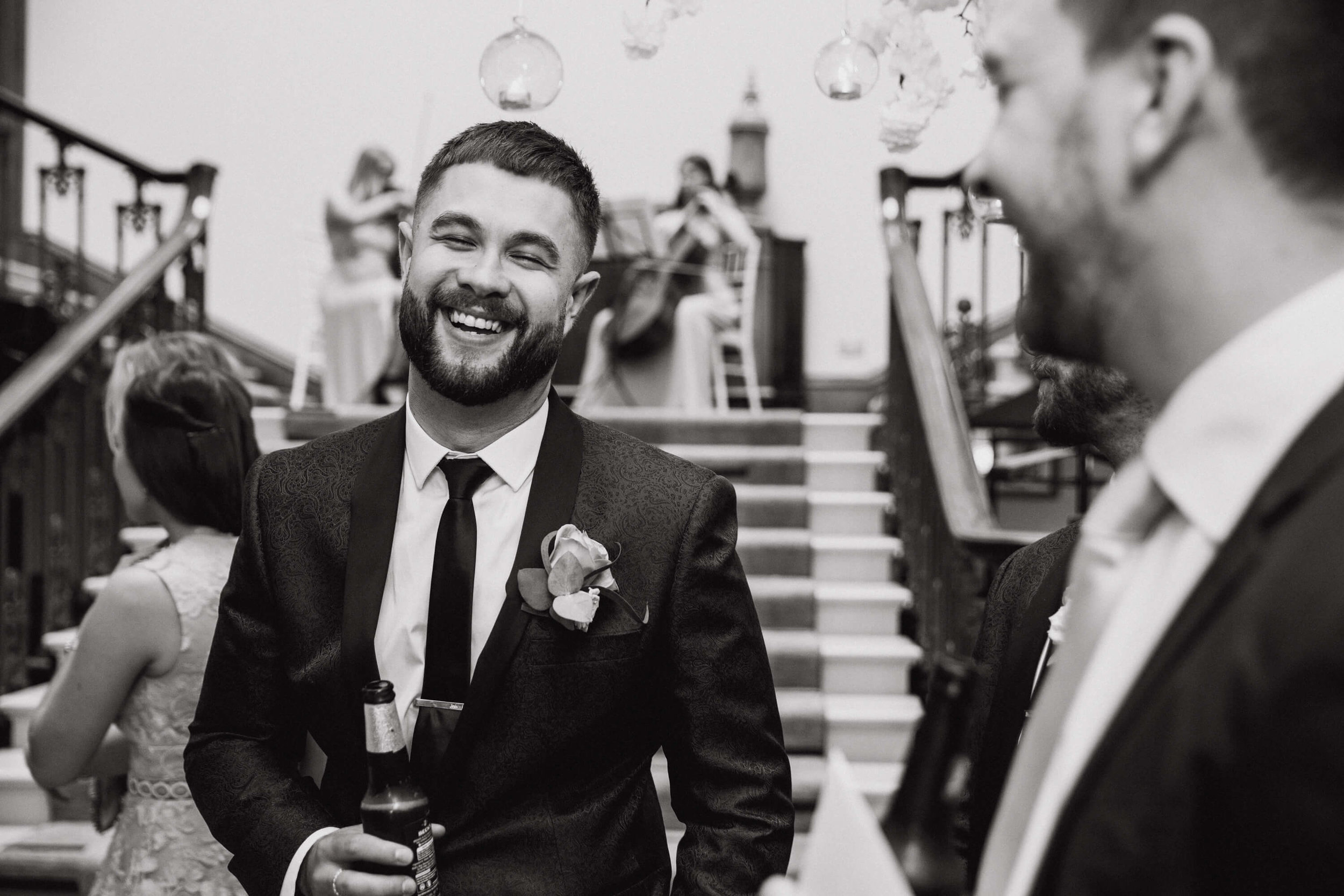 black and white photograph of groomsman laughing