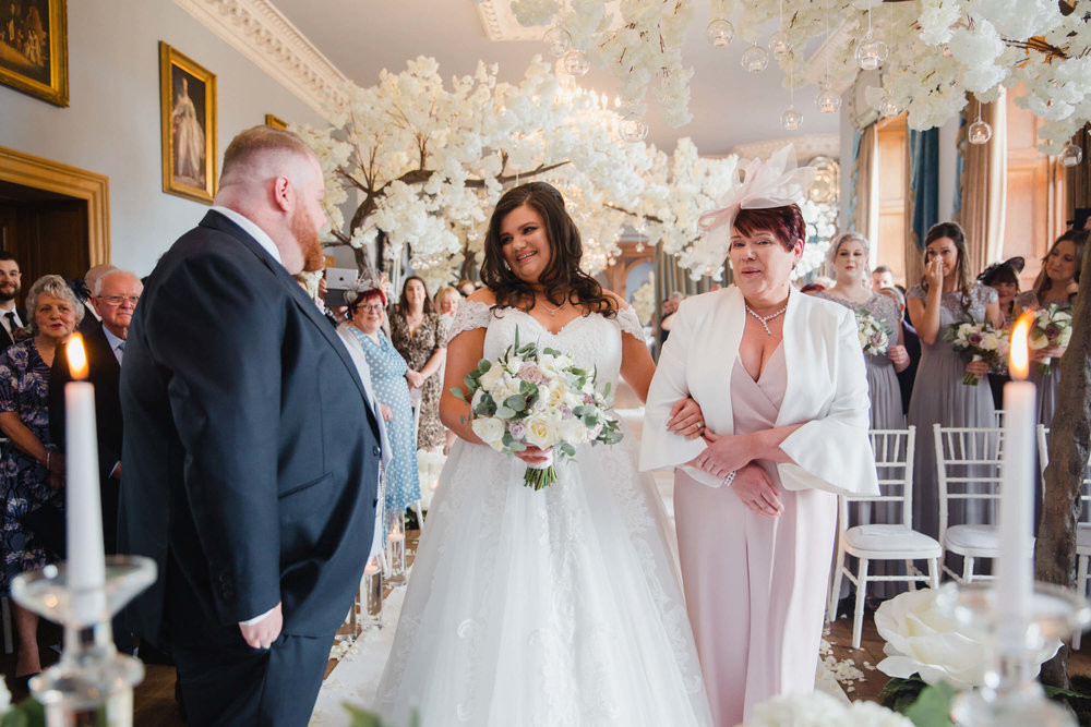 groom greeting bride at top of aisle for wedding ceremony at haigh hall