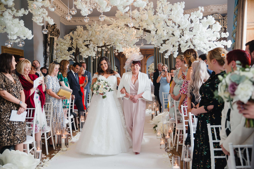 bride walking down aisle of blossom trees and candles at haigh hall