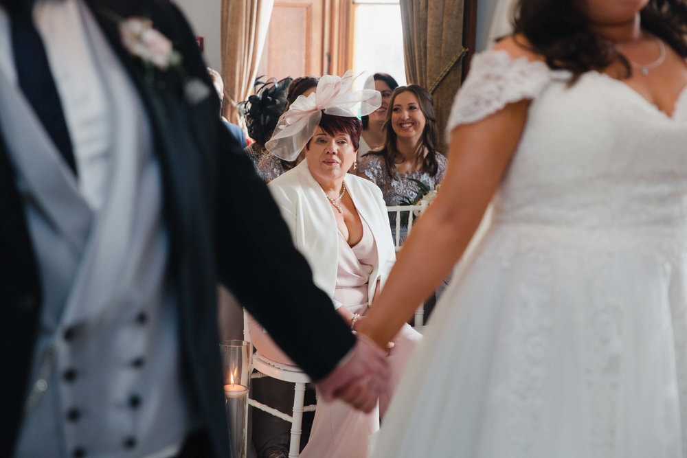 mother of bride watching bride exchange vows at haigh hall