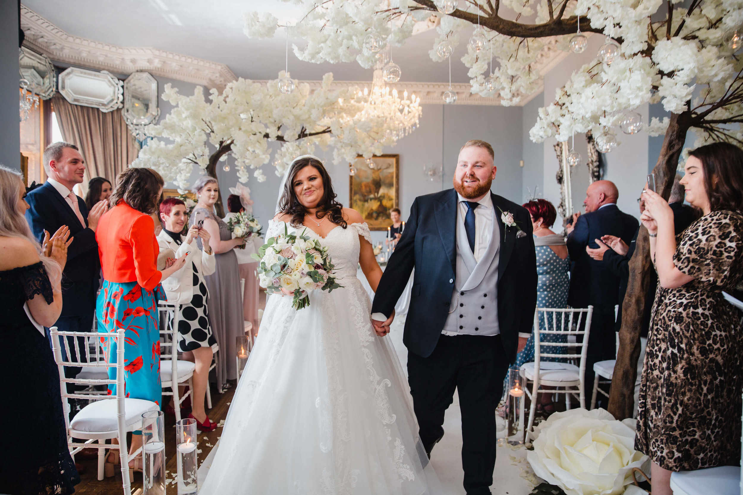 newlyweds holding hands congratulated by friends and family