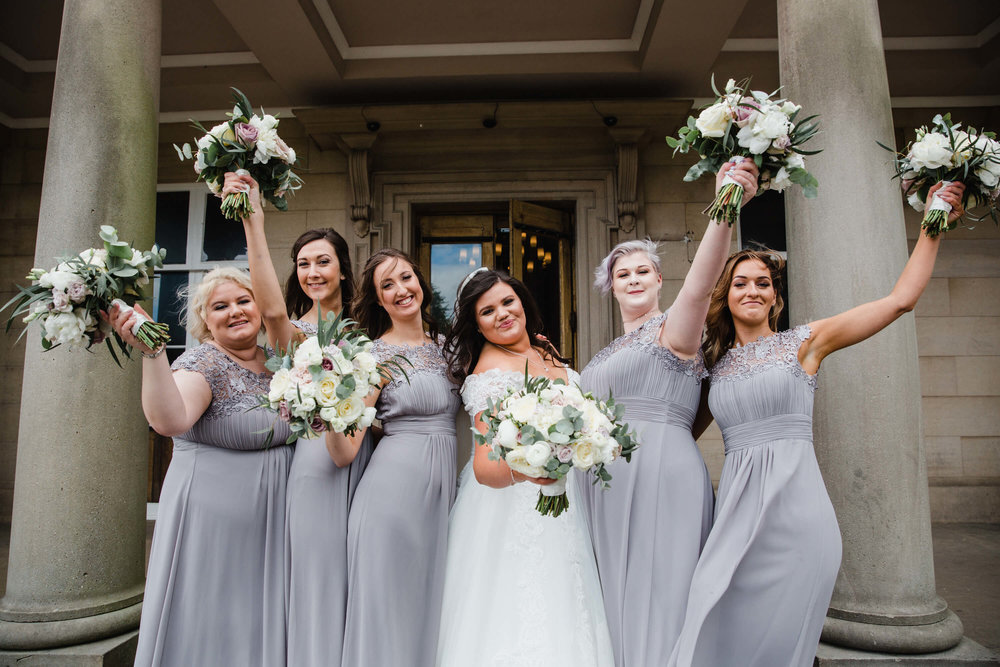 bridesmaids holding bouquets in air at haigh hall wedding venue