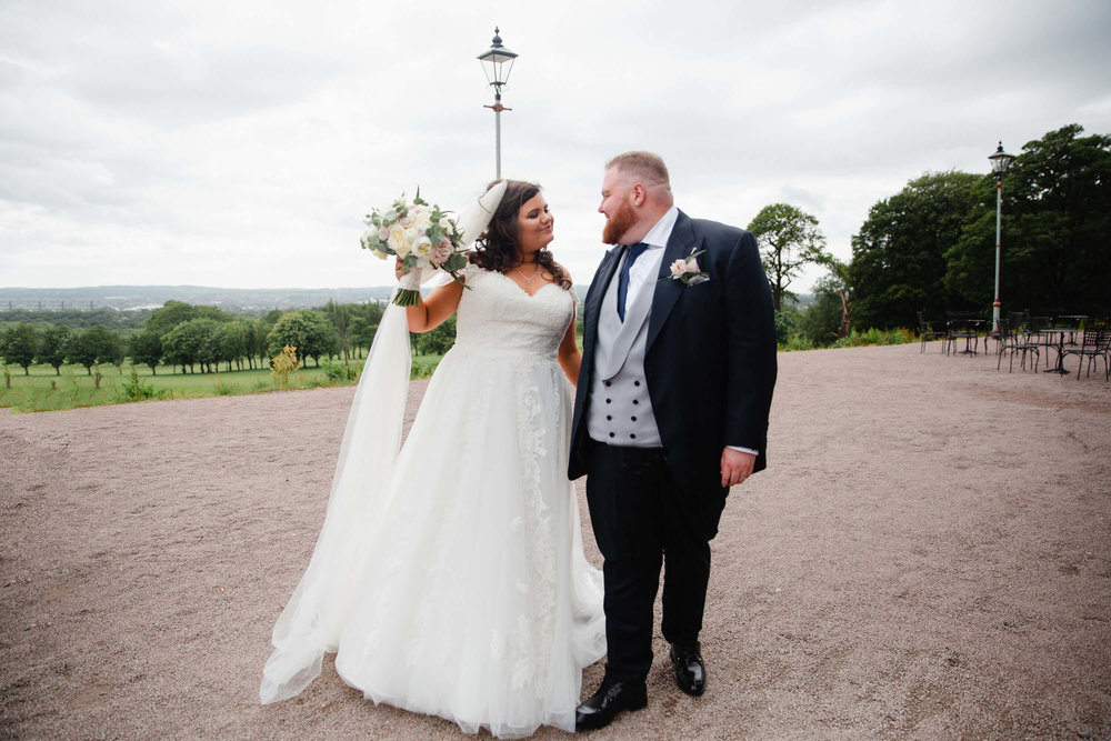 newlyweds holding bouquet of flowers in grounds of haigh hall