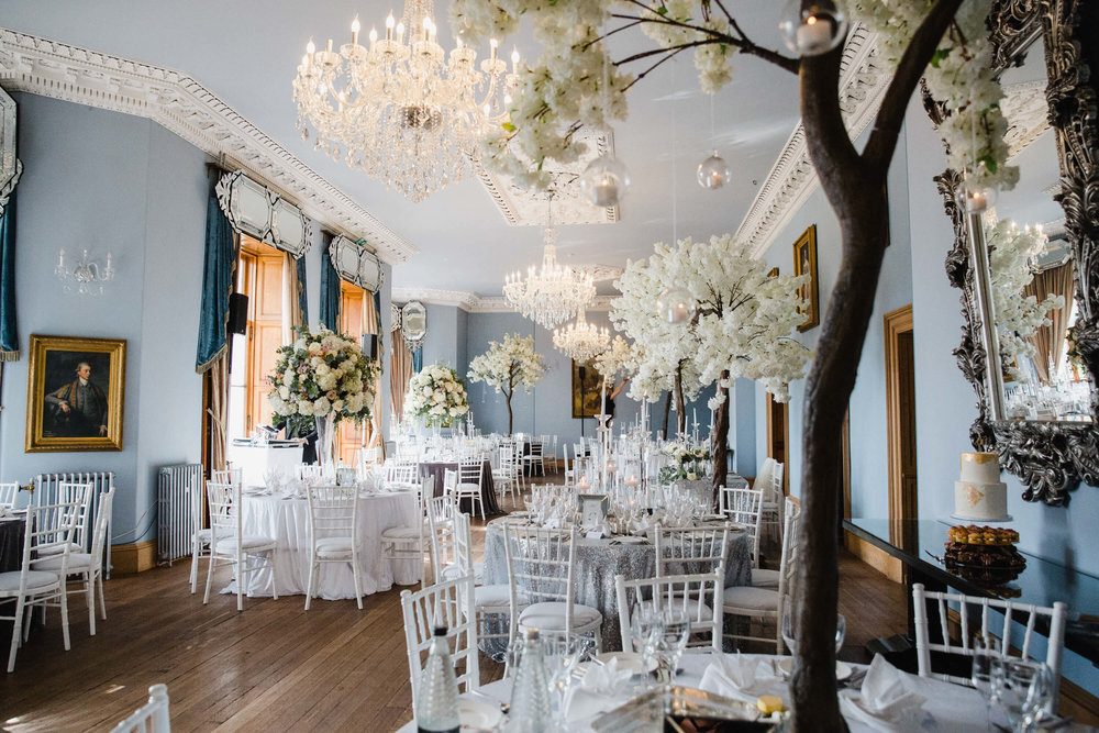 wedding breakfast table decorations of blossom trees and candles at haigh hall