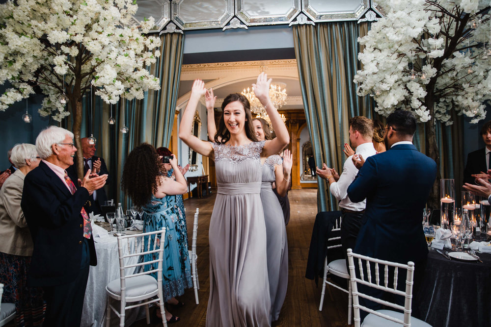 bridesmaids entering wedding breakfast room greeted by clapping wedding guests