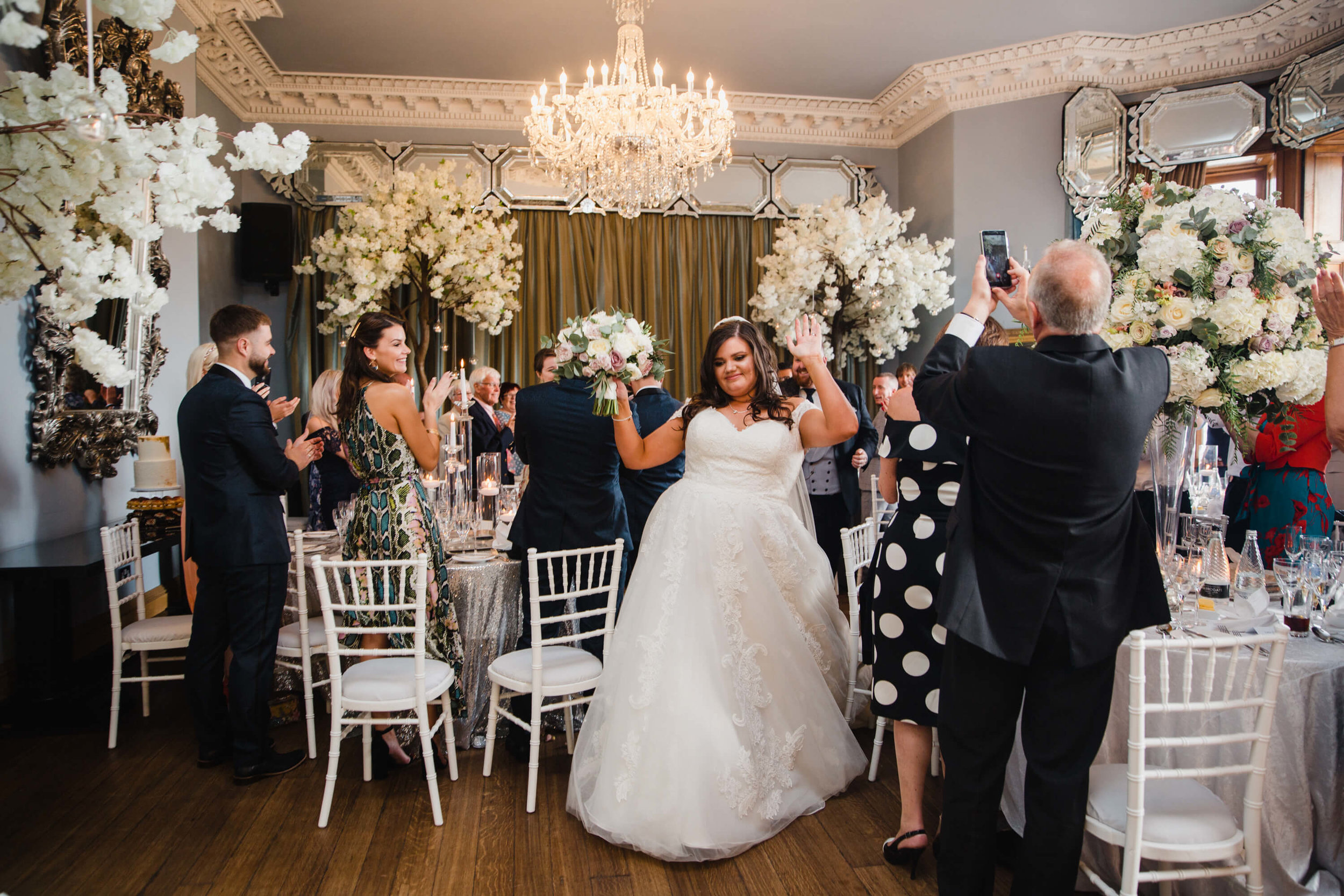 bride being cheered into wedding breakfast room